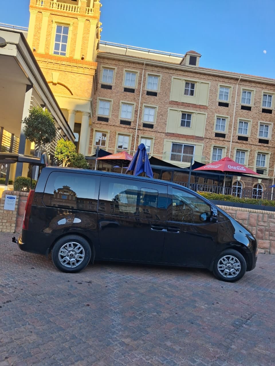 Black executive passenger van at a hotel entrance