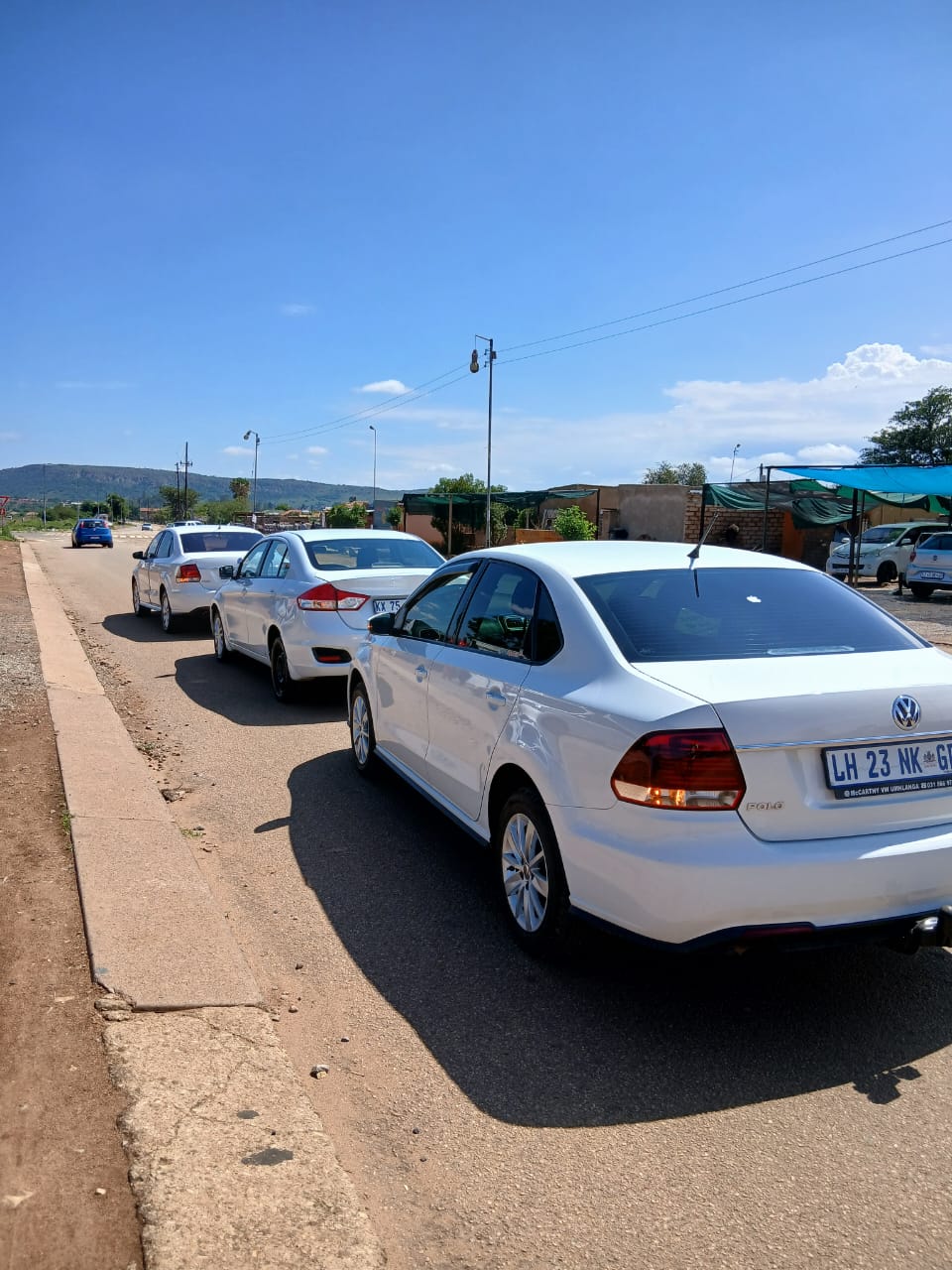 Rear view of white RR Elite sedans in a convoy